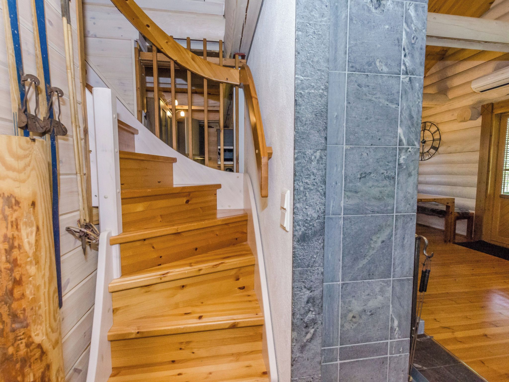 A wooden staircase with a stone wall on one side.