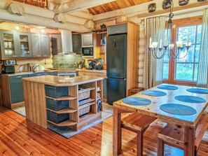 Une cuisine rustique avec un îlot central, des armoires en bois et un grand réfrigérateur.