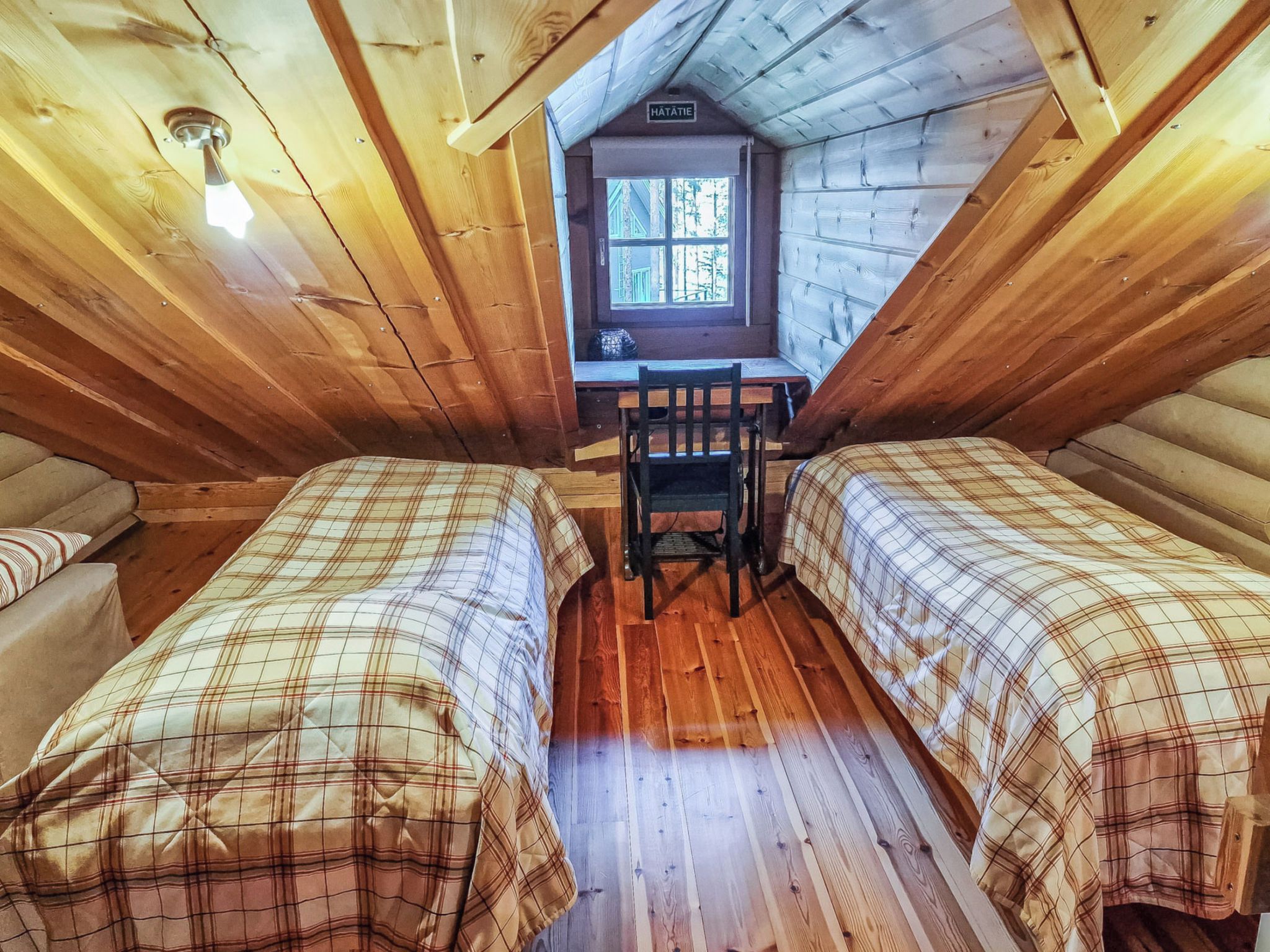 Eine Hütte mit zwei Betten, einem Schreibtisch und einem Fenster.