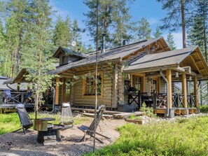 Une cabane en rondins dotée d’un porche et d’un espace extérieur aménagé pour s’asseoir.