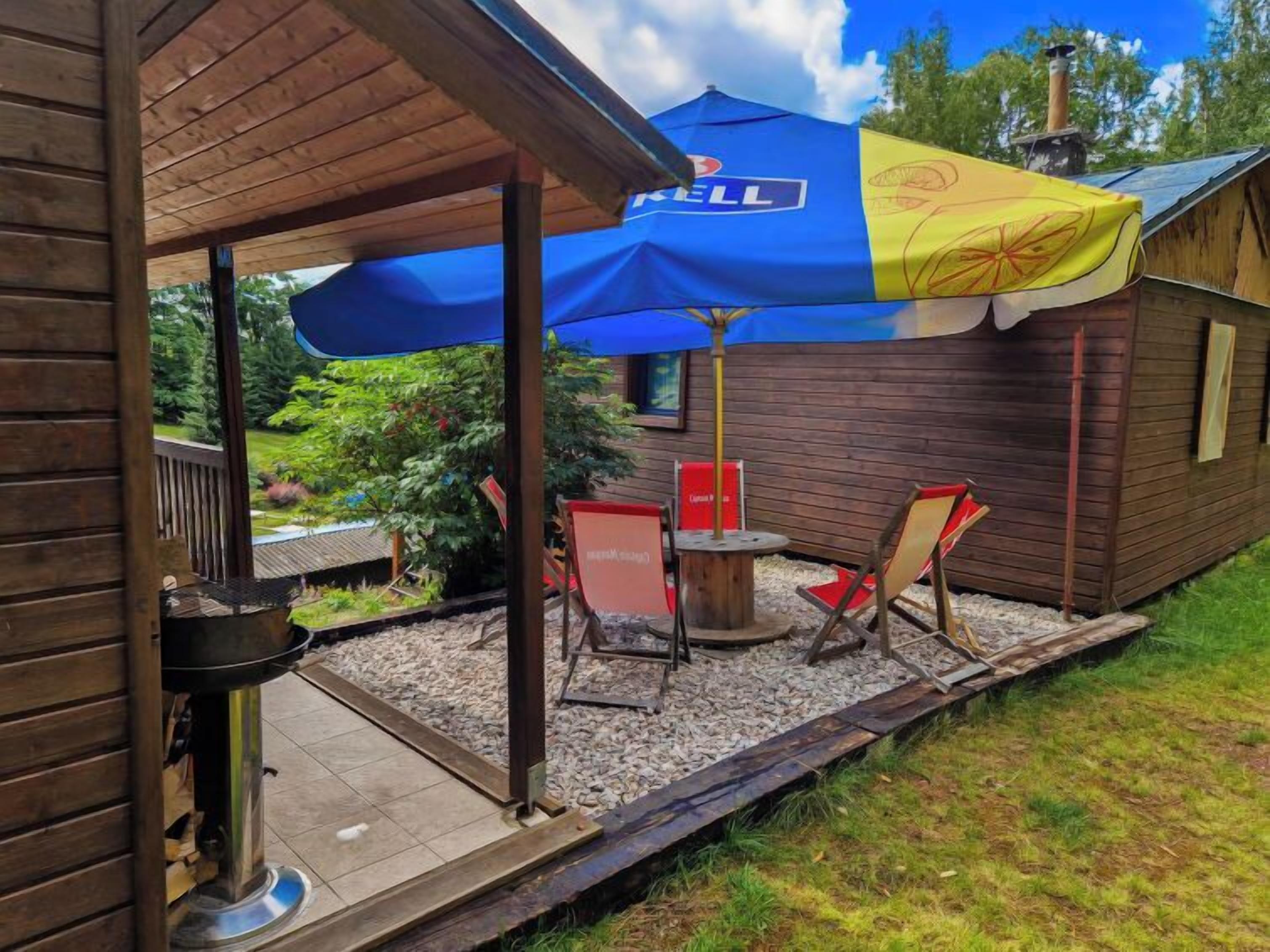 Una terraza de madera con mobiliario exterior y una parrilla.