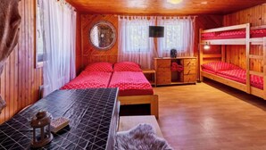 Una camera accogliente con soffitto in legno, uno specchio rotondo, un letto con biancheria rossa, un comò in legno e un tappeto in pelliccia.