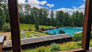 A wooden deck overlooking a swimming pool with lounge chairs and a grassy area.