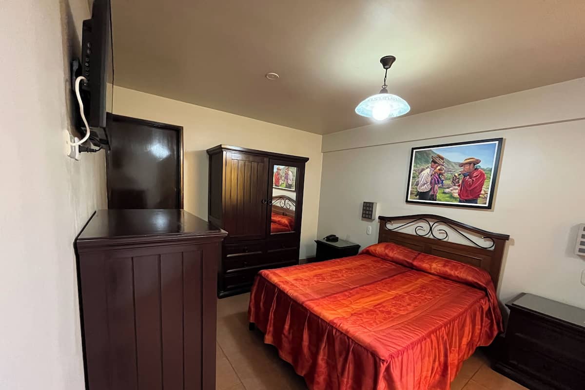 A bedroom with a bed, a wardrobe, a desk, and a ceiling light.