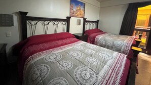 Dos llits amb capçaleres, un quadre a la paret i una finestra amb cortines.