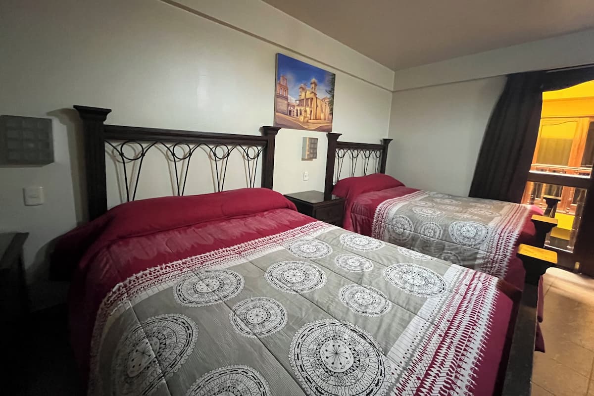 Two beds with headboards, a painting on the wall, and a window with curtains.