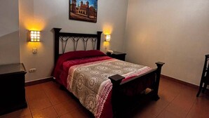 Un dormitori amb un llit, dues làmpades de nit, un quadre a la paret i un llum penjant.