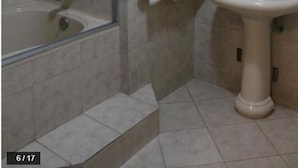 Un bany amb banyera, un lavabo, un mirall i un penjador de tovalloles.