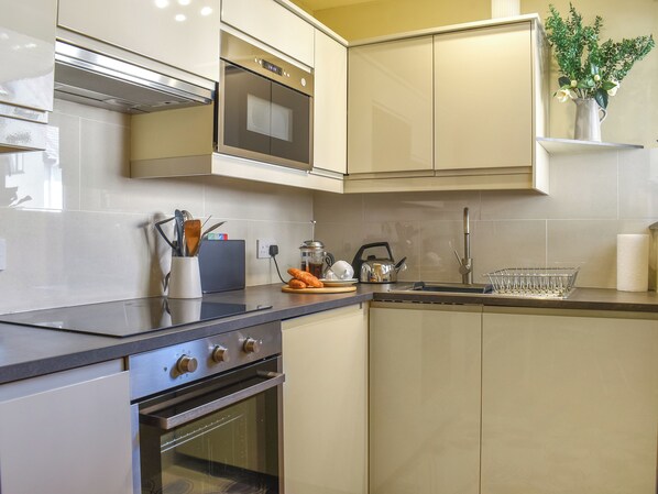 A modern kitchen with a built-in oven, a kettle, and a sink.