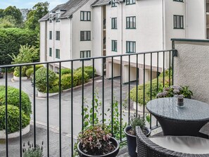 A balcony with a view of a building, potted plants, and outdoor furniture. - 2 bedroom accommodation in Bowness-on-Windermere (Bowness-on-Windermere)