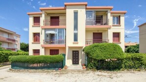 A multi-story residential building with balconies, a central entrance, and surrounding greenery. - Les Vagues by Interhome (Saint Cyr sur mer Les Lecques)