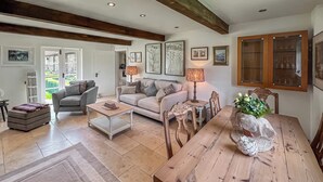 Een ruime woonkamer met een houten eettafel, twee banken, een salontafel en een vloerkleed.