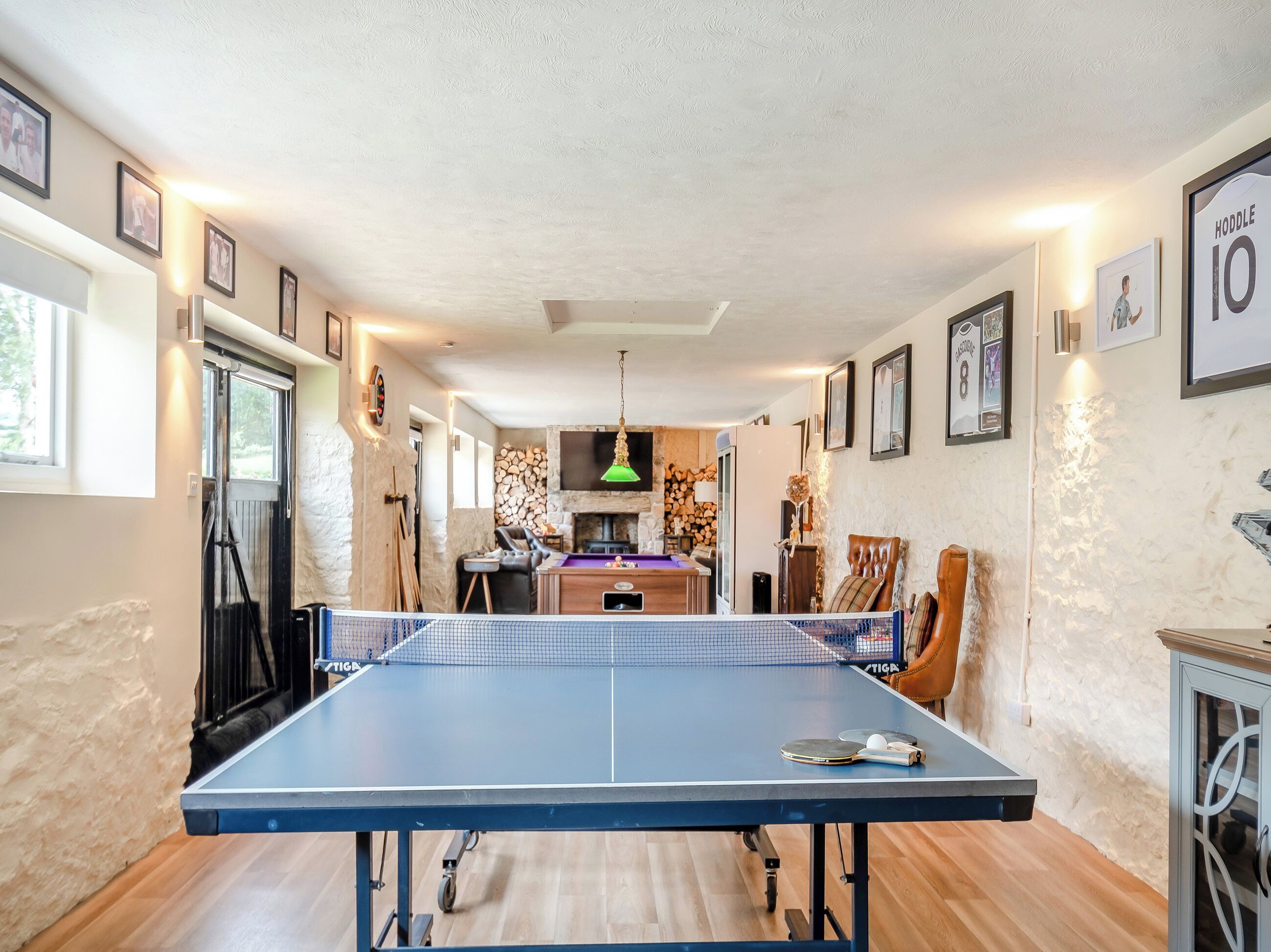 Une table de ping-pong dans une pièce qui comprend une cheminée, une table à manger et une chaise.
