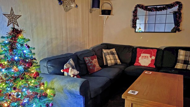 Un salon avec un sapin de Noël, un canapé et une table basse.