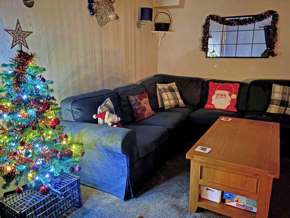 A living room with a Christmas tree, a couch, and a coffee table.