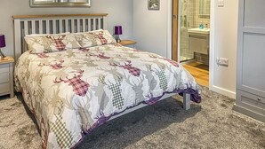 Une chambre à coucher comprenant un lit, une table de chevet, une lampe de chevet, un miroir et une salle de bain visible à travers une porte ouverte.