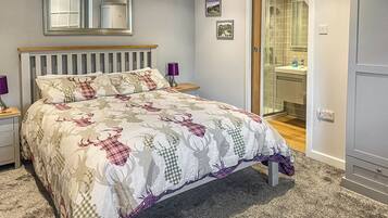 A bedroom with a bed, a nightstand, a bedside lamp, a mirror, and a bathroom visible through an open door.