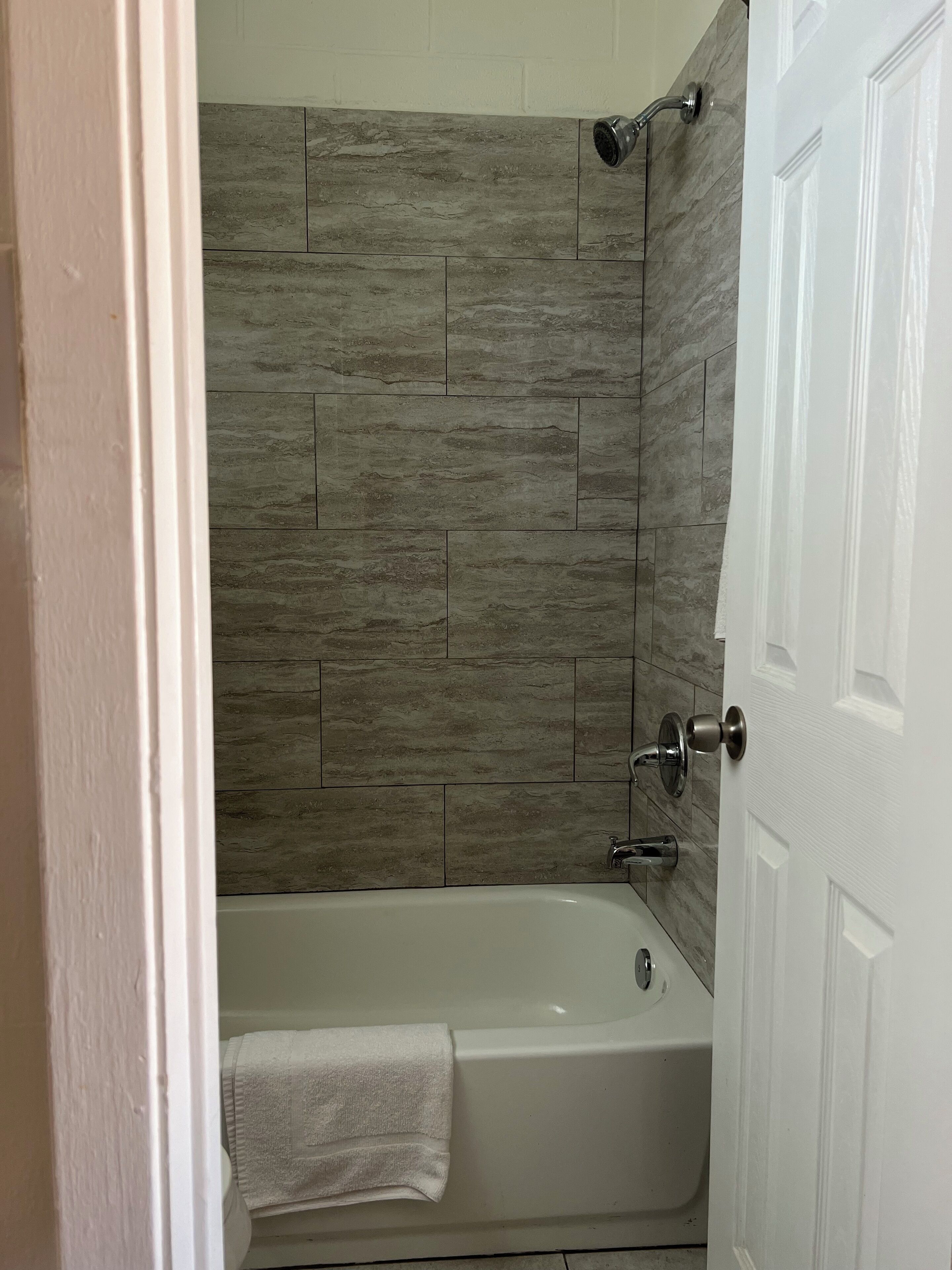 Un baño con bañera, ducha y paredes de azulejos.