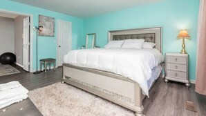 A bedroom with a bed, a nightstand, a lamp, a small stool, and a door. - EverStay Duplex “Suite B” Close to Everything  (charlotte)