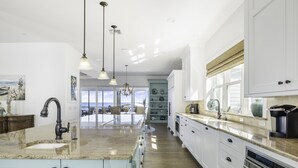 A spacious kitchen with a large island, white cabinetry, and pendant lighting. - Life Changing Views from this Luxury 3 Bedroom Bayfront Home! (Captiva)