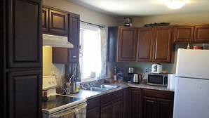 Une cuisine avec des meubles de rangement en bois foncé, une cuisinière blanche, un four à micro-ondes et un réfrigérateur.