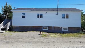 Une maison à deux étages, avec une antenne parabolique bien visible, un petit porche et une allée gravillonnée.