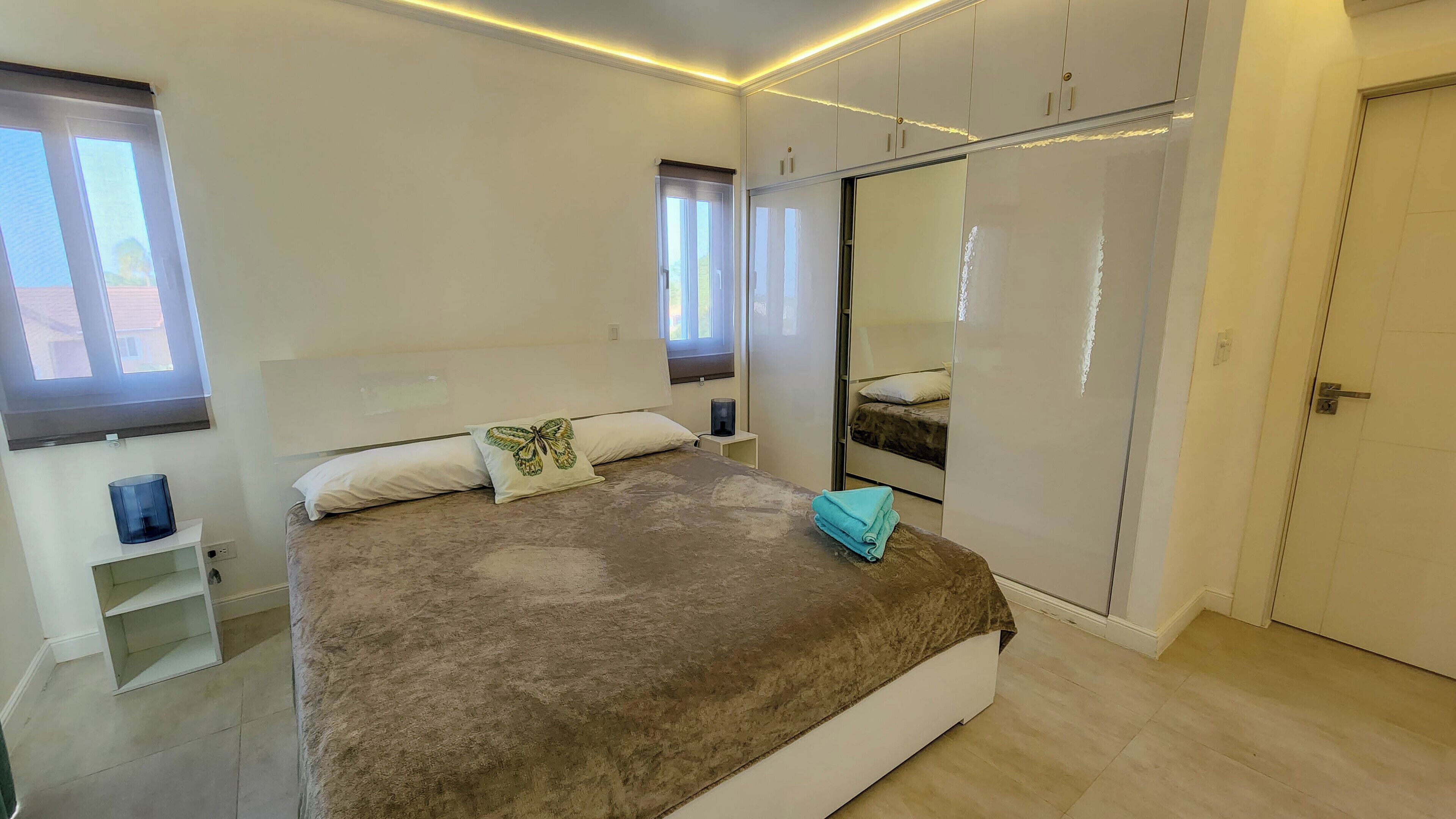 Een slaapkamer met een bed, een kledingkast, een nachtkastje en een raam.