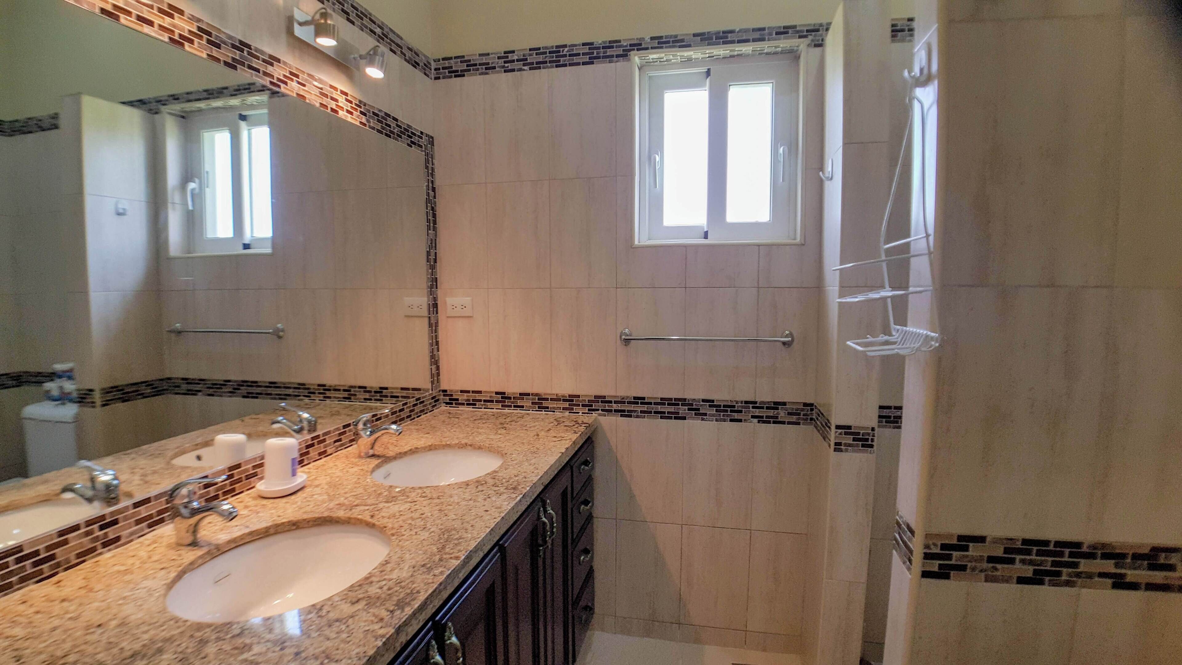 A bathroom with two sinks, a large mirror, and a shower area.