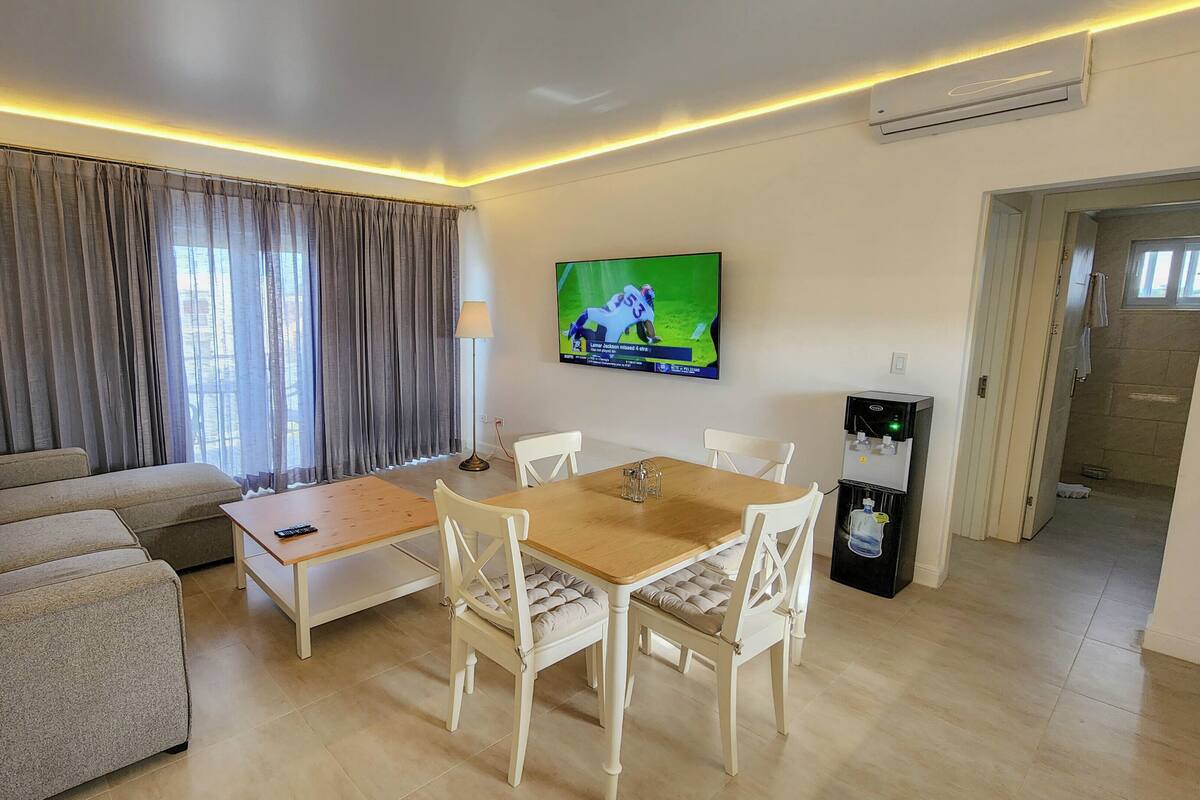 Een woonkamer met een bank, een salontafel, een televisie en een waterdispenser.