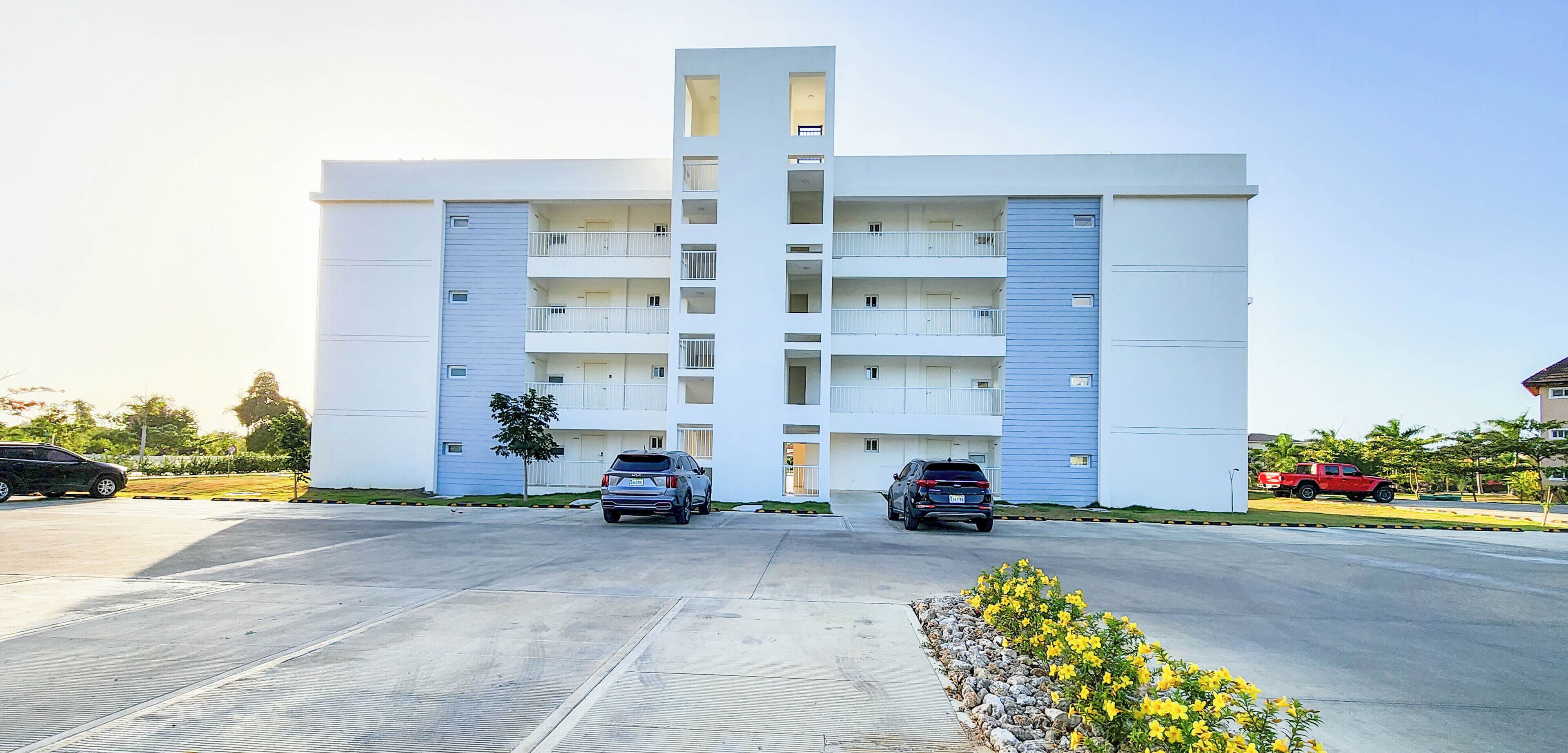 A multi-story residential building with a parking lot in front.