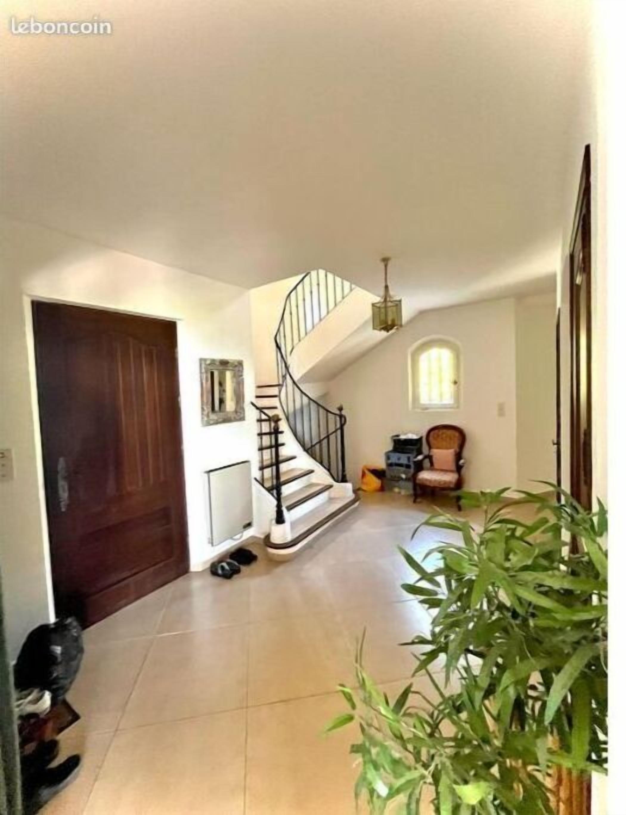 A spacious hallway with a wooden door, a spiral staircase, and a potted plant.
