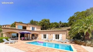 Une maison à deux étages dotée d’une piscine, d’un espace salon extérieur et d’une terrasse couverte.