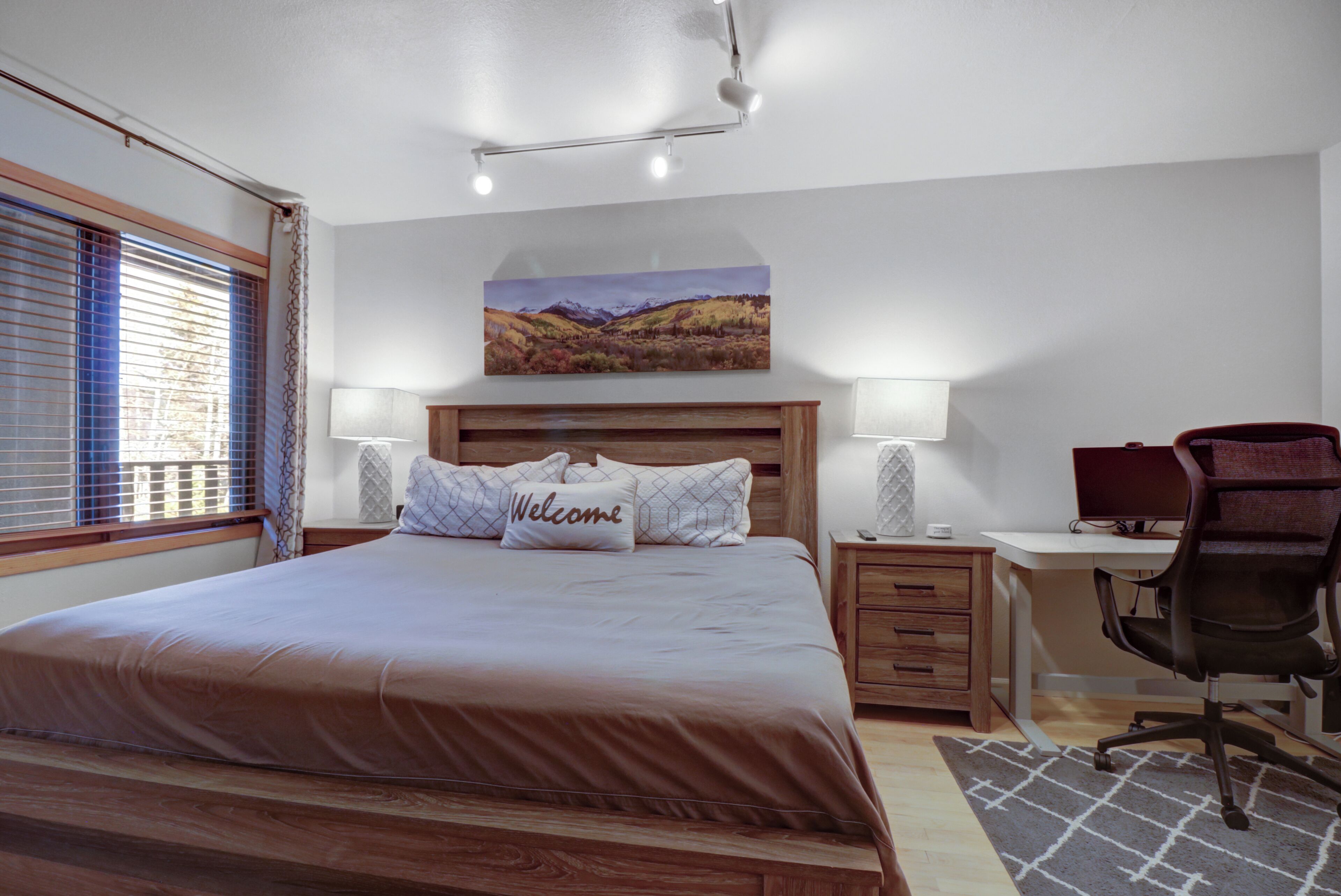 A bedroom with a large bed, bedside tables, a desk, and a chair.
