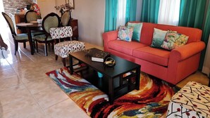 A living room with a red sofa, patterned cushions, a coffee table, and a colorful rug.