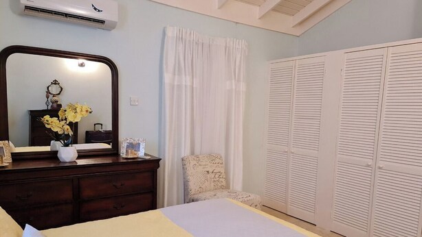 A bedroom with a bed, dresser, mirror, and a wardrobe.