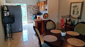 A dining area with a round table, chairs, and a vase of flowers.