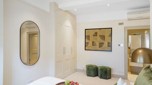 A bedroom with a bed, a breakfast tray, a mirror, a wardrobe, and a painting on the wall.