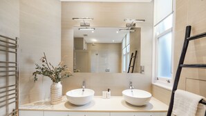 A modern bathroom with two sinks, a large mirror, and a towel rack.