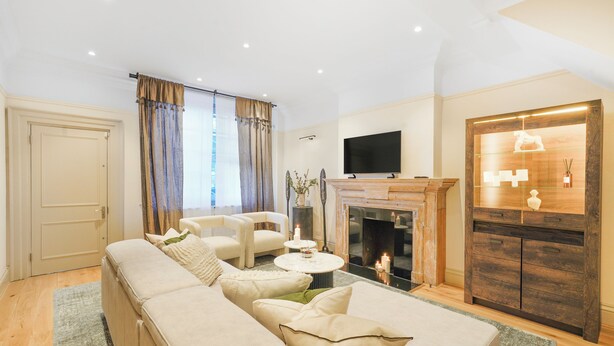 A modern living room with a sofa set, a fireplace, and a television.