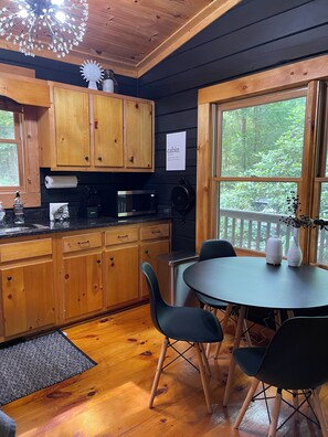 Una cocina estilo cabaña con armarios de madera, un microondas y un comedor con mesa y sillas.