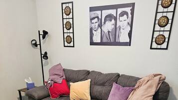 Een woonkamer met een bank, een salontafel, een lamp en een ingelijst schilderij aan de muur.