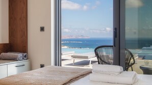 Ein Schlafzimmer mit großem Fenster mit Blick auf einen Pool und das Meer.