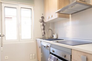 A compact kitchen with a sink, stove, and cabinets.