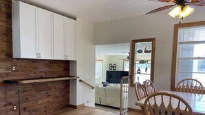 A modern kitchen with wooden cabinetry, a built-in bench, and a dining area with wooden chairs and a table.