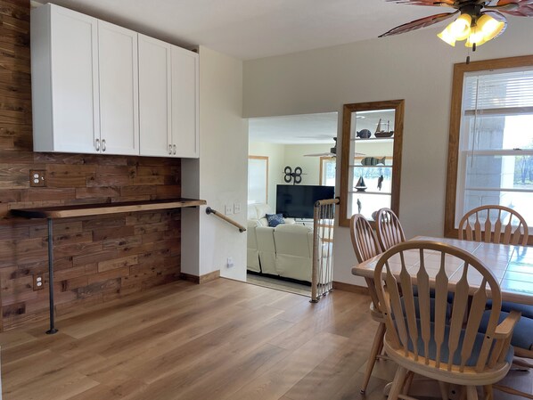 Una cocina moderna con armarios de madera, un banco empotrado y un comedor con sillas y mesa de madera.