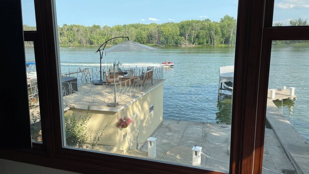 A view from a window overlooking a dock area with a covered seating area and a boat.