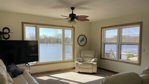 A living room with a large window, a ceiling fan, a TV, and a chair.
