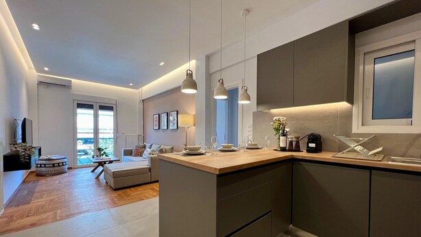 A modern kitchen with a central island, pendant lighting, and a view to the living area. - AgiasFoteinis20  ·  Nea Smirni Square chic apartme (Athens)