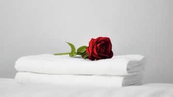 Una toalla blanca doblada con un solo rosal encima.