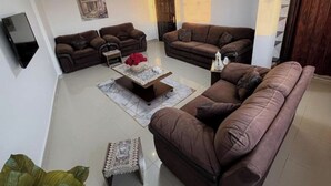 A living room with two brown sofas, a coffee table, and a TV mounted on the wall.